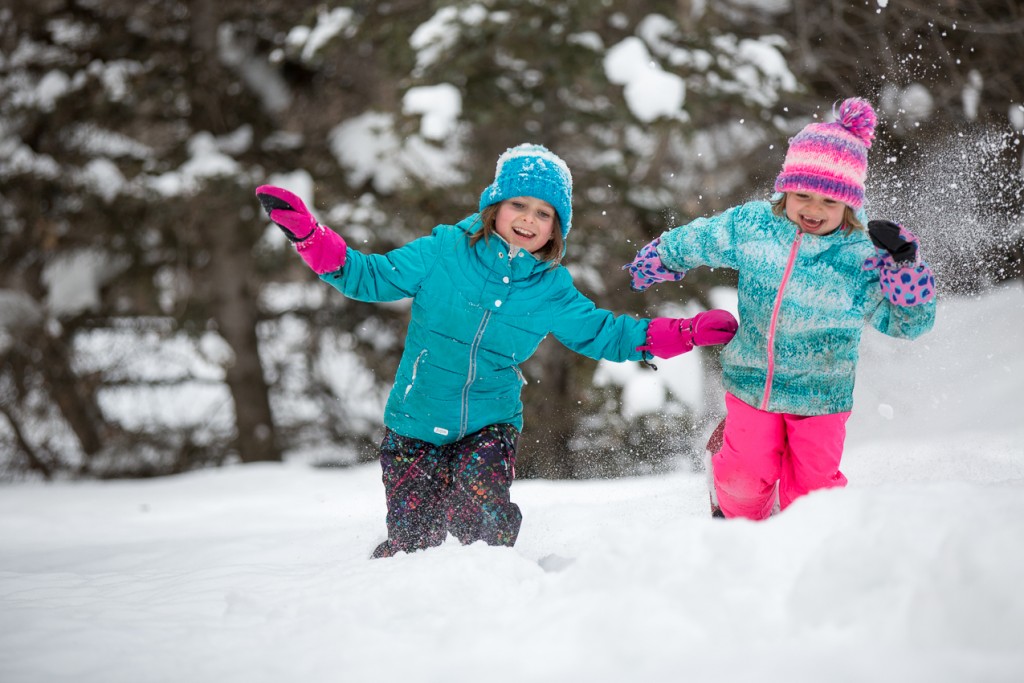 two young girls playing in the deep snow laughing and smiling