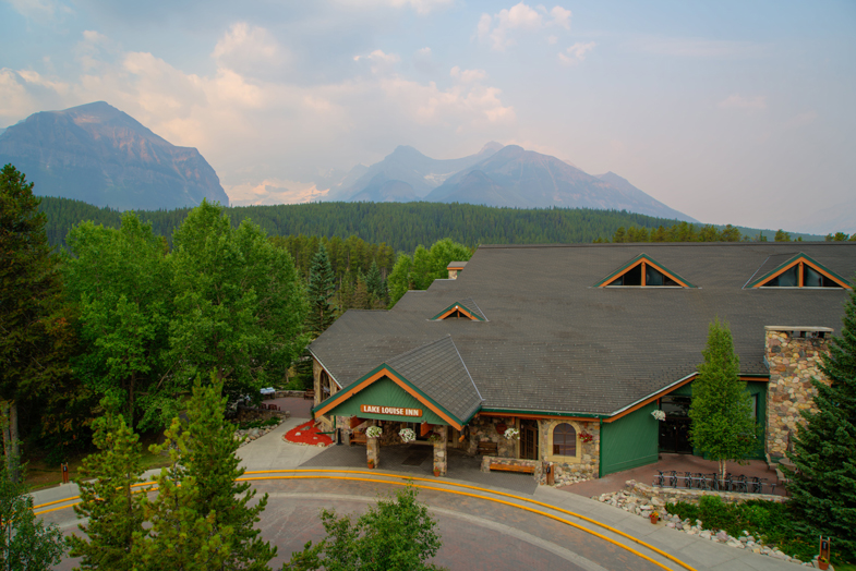 aerial view of Lake Louise Inn surrounded by a sea of trees leading to majestic mountains