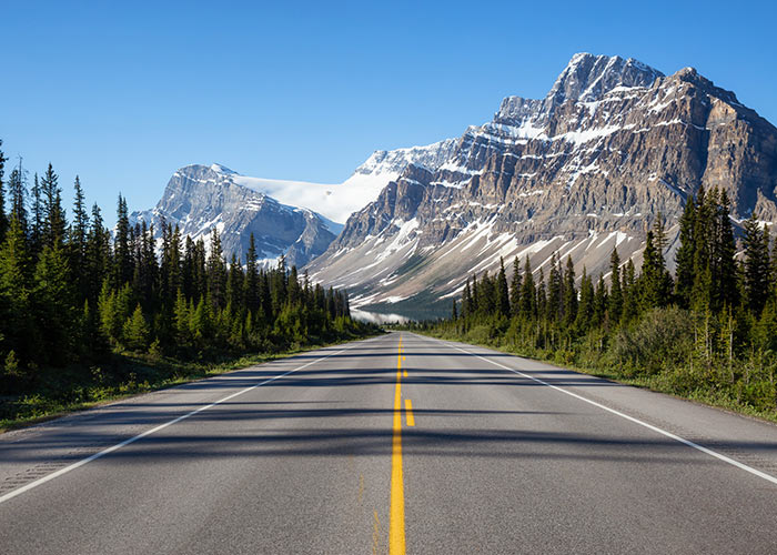 Road to Lake Louise surrounded by forest and mountain peaks