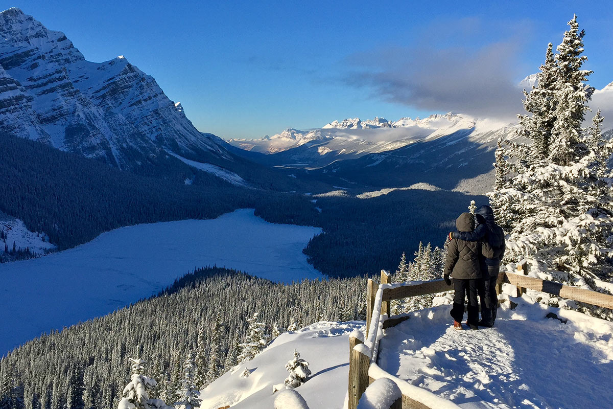 Couple embracing on overlook of Peyto Lake on blue sky winter day