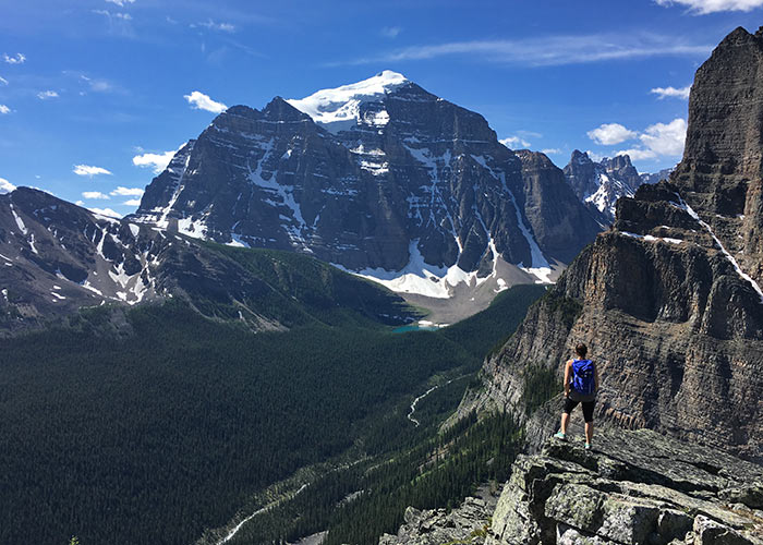 Hiker looking over view of Mount Temple from large rock