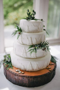 layered wedding cake decorated with forest images and natural accents