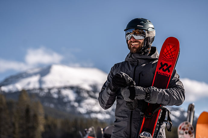 Man in ski gear holding a snowboard