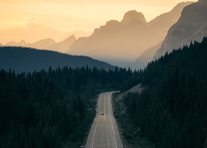 Car on a road at dusk with mountains on the background