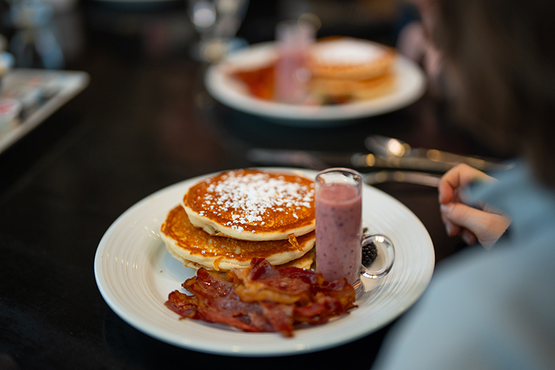 Breakfast dish with pancakes, bacon and strawberry smoothie.